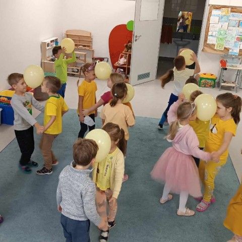 Powiększ obraz: Dzieci tańczą w parach trzymając żółte balony pomiędzy sobą