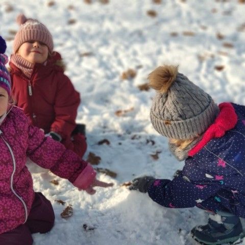 Powiększ obraz: Dziewczynki lepią bałwana ze śniegu