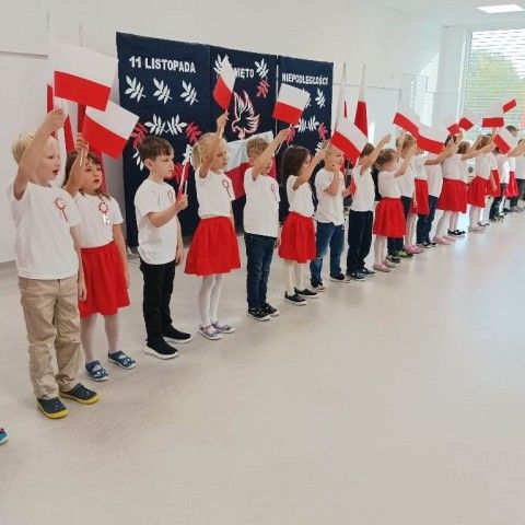 Powiększ obraz: Dzieci z grupy 1 śpiewają piosenkę i wymachują biało-czerwonymi flagami