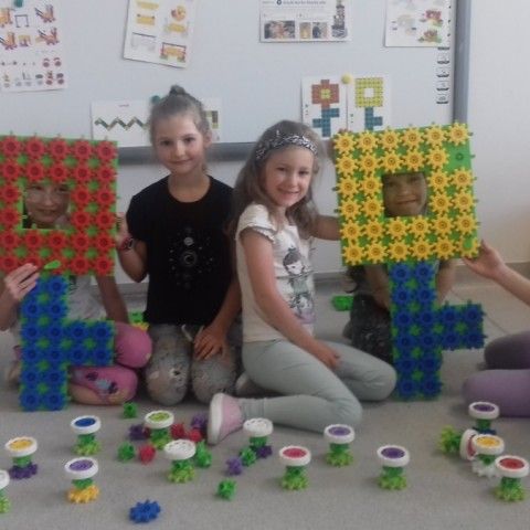 Powiększ obraz: Dziewczynki prezentują kolorowe kwiatki skonstruowane z klocków Korbo