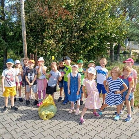 Powiększ obraz: Dzieci z dumą prezentują worek z posprzątanymi śmieciami.