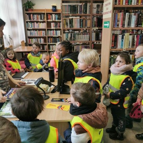 Powiększ obraz: Dzieci słuchają ciekawostek na temat biblioteki