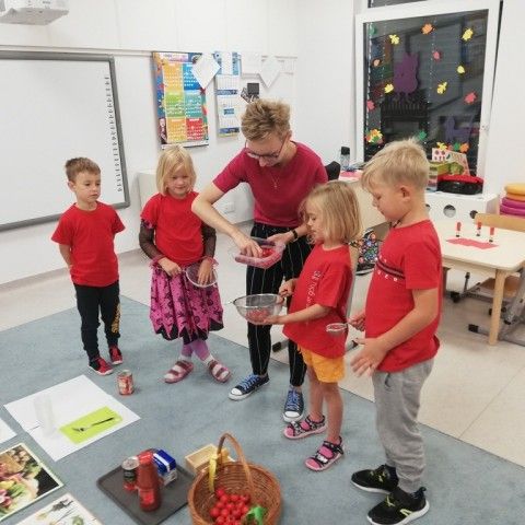 Powiększ obraz: Grupa dzieci podczas zabawy matematycznej polegającej na przeliczaniu pomidorów
