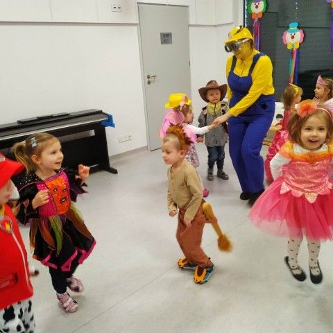 Powiększ obraz: Grupa dzieci tańczy na udekorowanej sali wraz z przebraną za Minionką Panią
