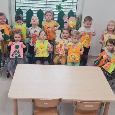 Powiększ obraz: Dzieci prezentują swoje prace plastyczne – postać Pani Wiosny wykonany z kolorowej bibuły i kwiatów wyciętych z kolorowego papieru