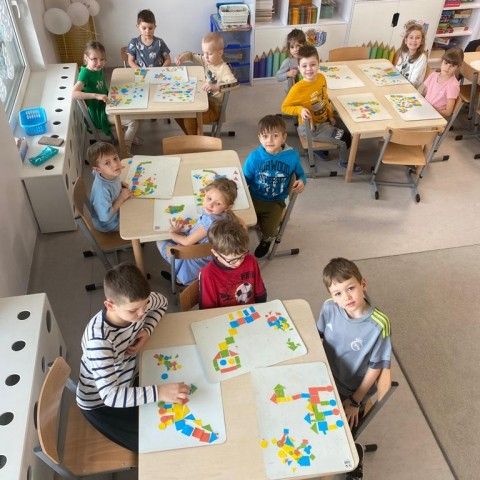 Powiększ obraz: Dzieci tworzą obrazy dinozaurów z wykorzystaniem mozaiki geometrycznej