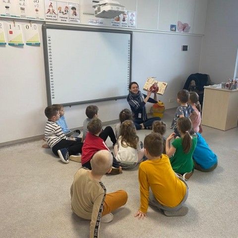 Powiększ obraz: Dzieci słuchają opowiadania o dinozaurach