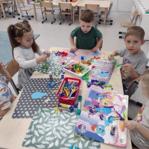 Powiększ obraz: Dzieci tworzą pracę plastyczną przy stoliku